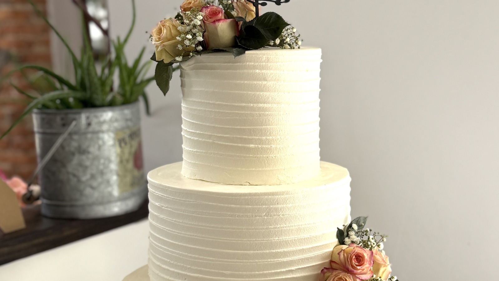 Tiered wedding cake with soft roses and topper from Classic Bakery