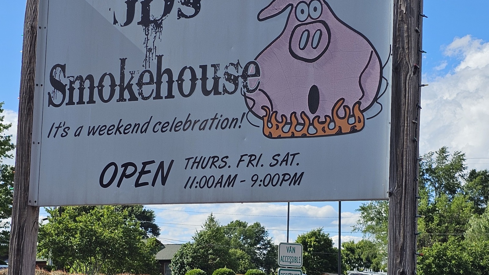 Roadside JD's Smokehouse sign in Rutherford College with hours and pink pig logo