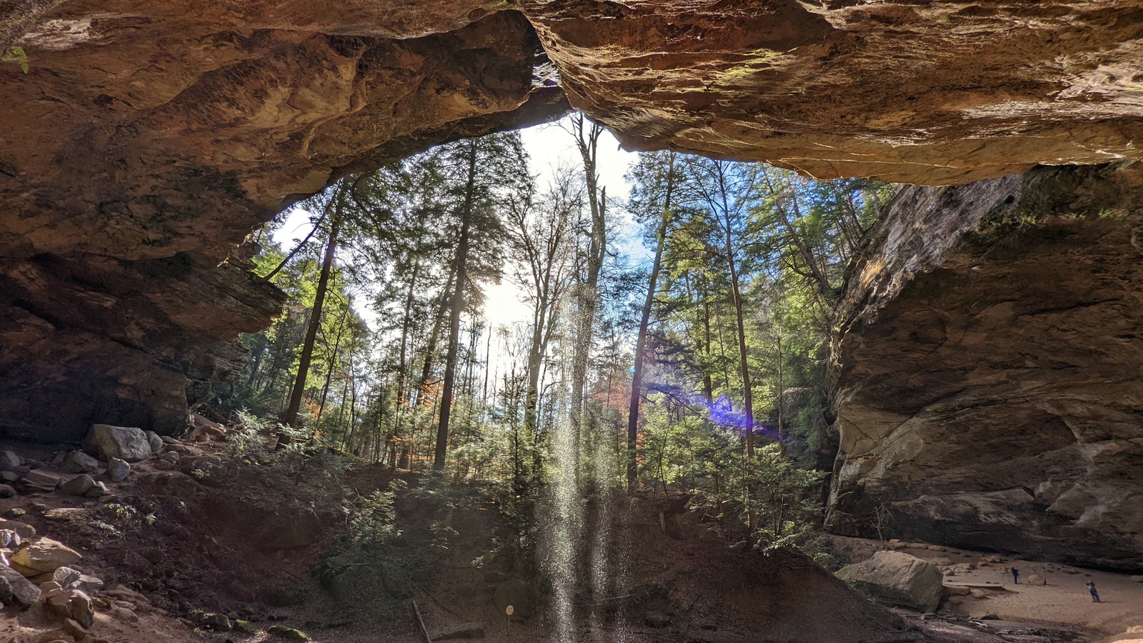 View outward from beneath a towering rock overhang at Hocking Hills State Park