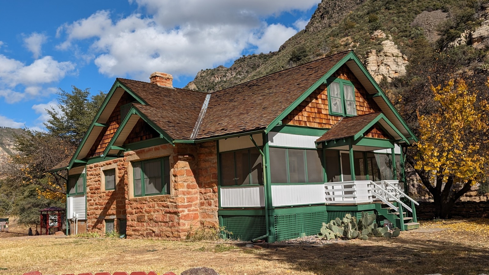 Historic Pendley Homestead house with green trim beneath red canyon walls