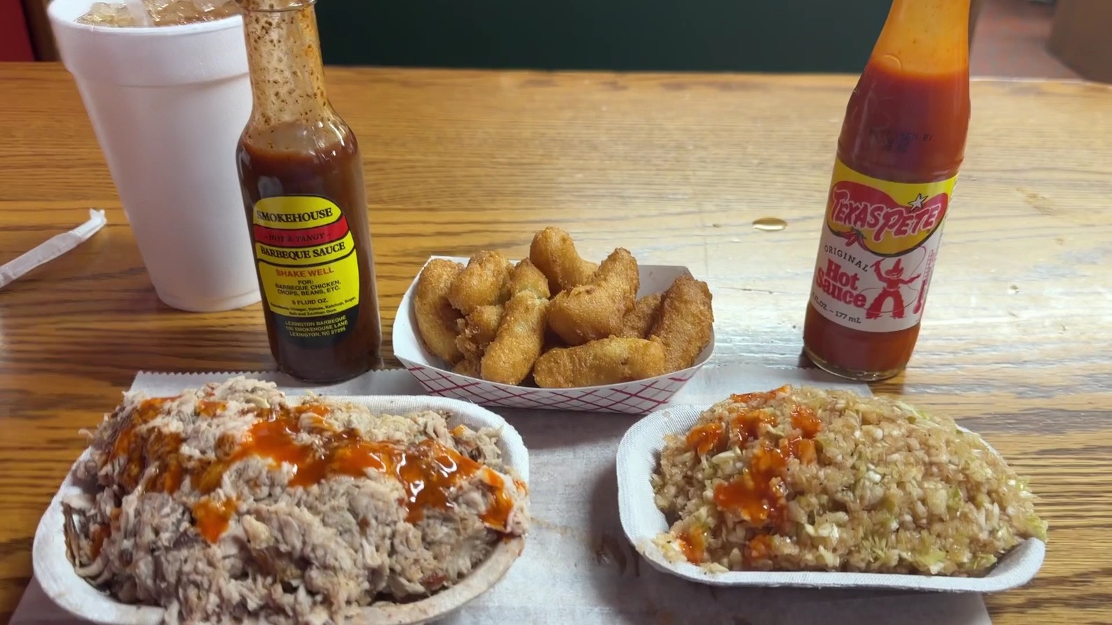 Barbecue tray, hush puppies, and sauce bottles on a table at Lexington Barbecue