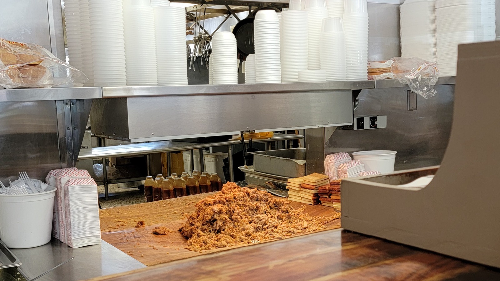 Chopped pork piled on the wooden chopping block beneath the counter and menu boards