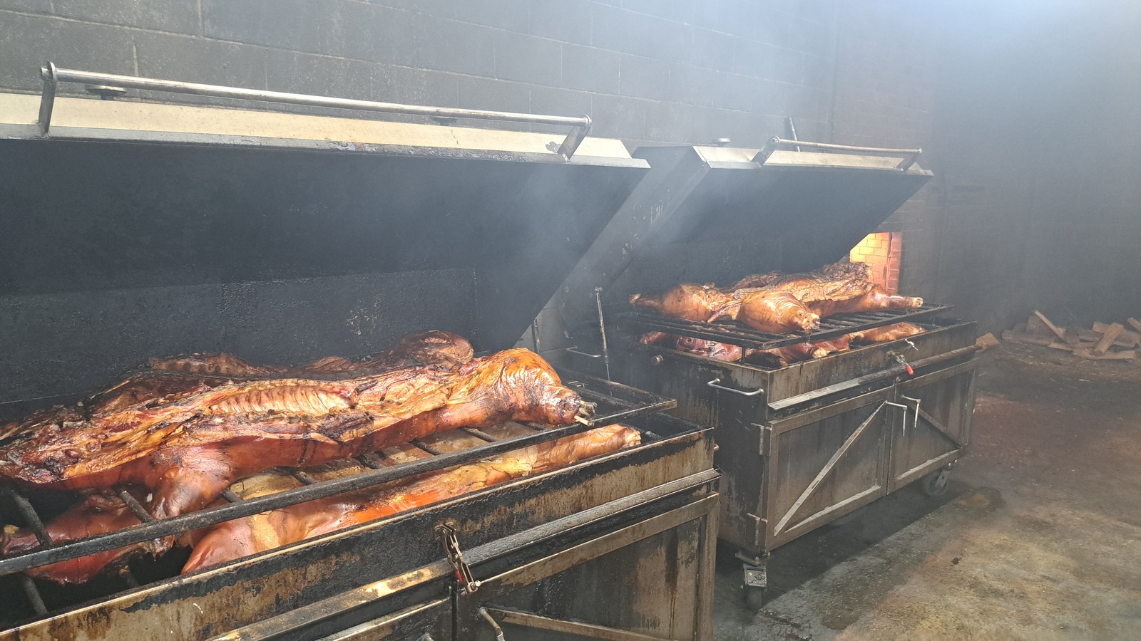 Whole hogs cooking in the smoker at Skylight Inn BBQ under warm pit light