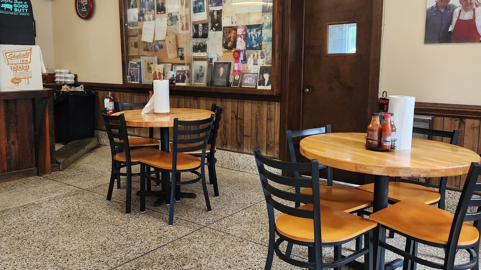 Dining room tables and wood-paneled walls inside Skylight Inn BBQ