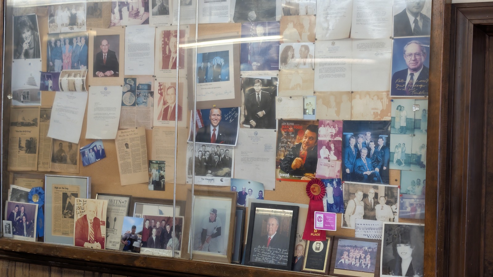 Large memorabilia display wall filled with photos, letters, awards, and clippings at Skylight Inn BBQ