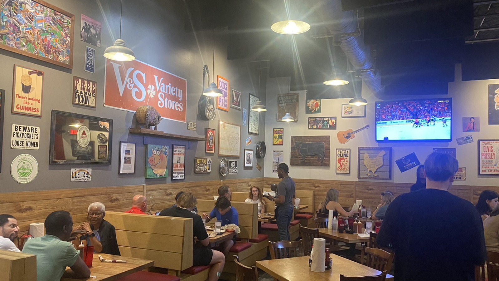 Booths beneath vintage wall art at Midwood Smokehouse in Charlotte.