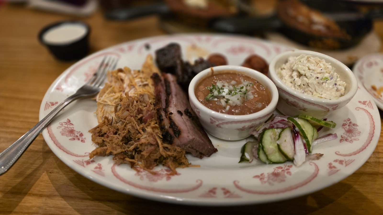 A mixed barbecue plate with pulled pork, brisket, beans, slaw, and pickles at Midwood Smokehouse.
