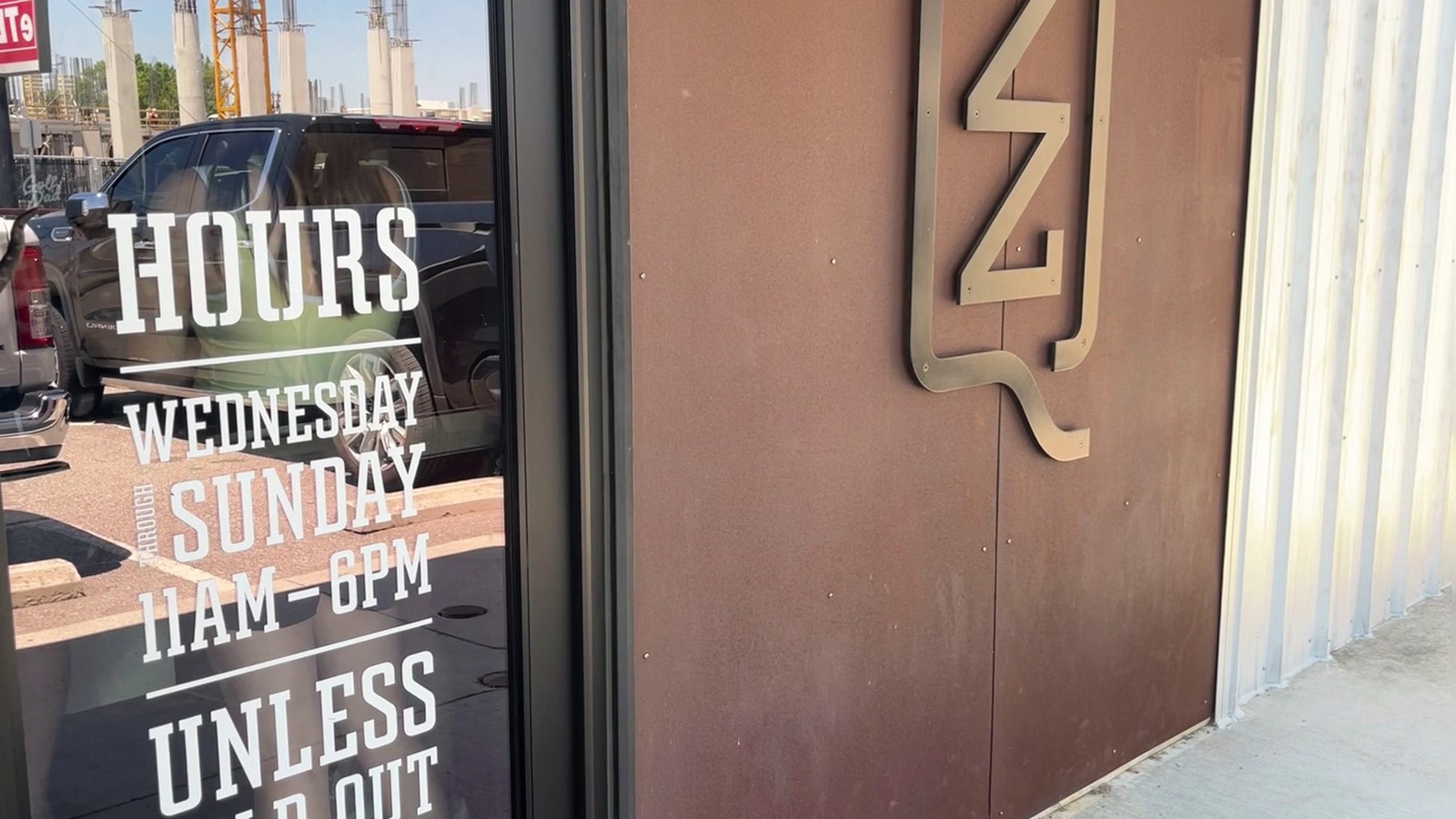 Front entry with ZZQ logo plaque and posted service hours at ZZQ Texas Craft Barbeque
