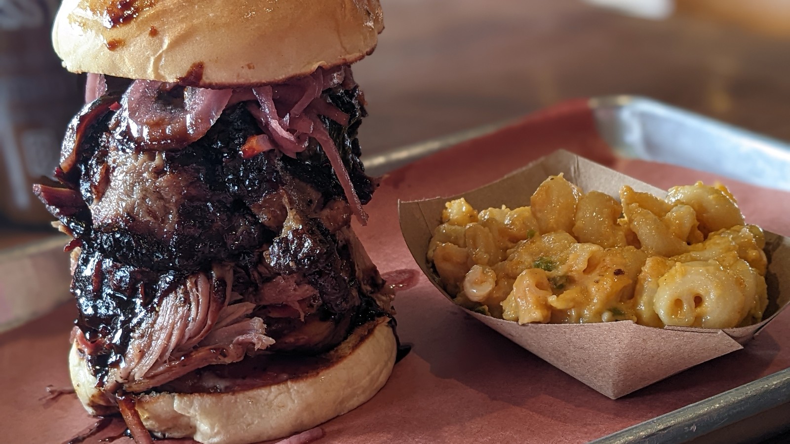 Tall smoked meat sandwich with pickled onions beside jalapeno mac and cheese at ZZQ Texas Craft Barbeque