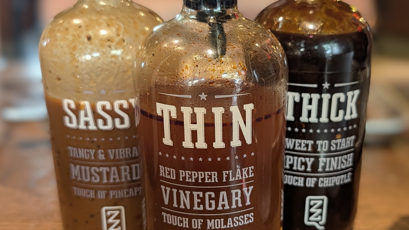 Thin, Thick, and Sassy house barbecue sauces lined up on a table at ZZQ Texas Craft Barbeque