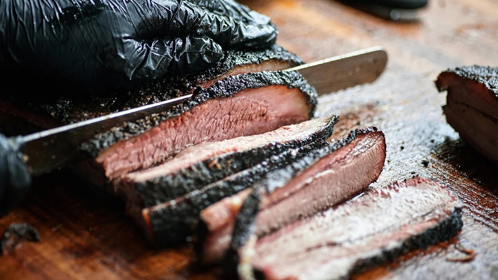 Sliced brisket with dark bark and a rosy smoke ring on the cutting board at ZZQ Texas Craft Barbeque
