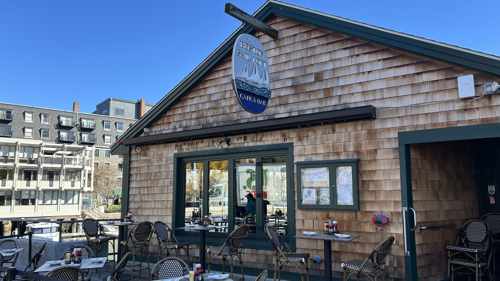 Boston Sail Loft facade and patio seating beside the harbor in daylight