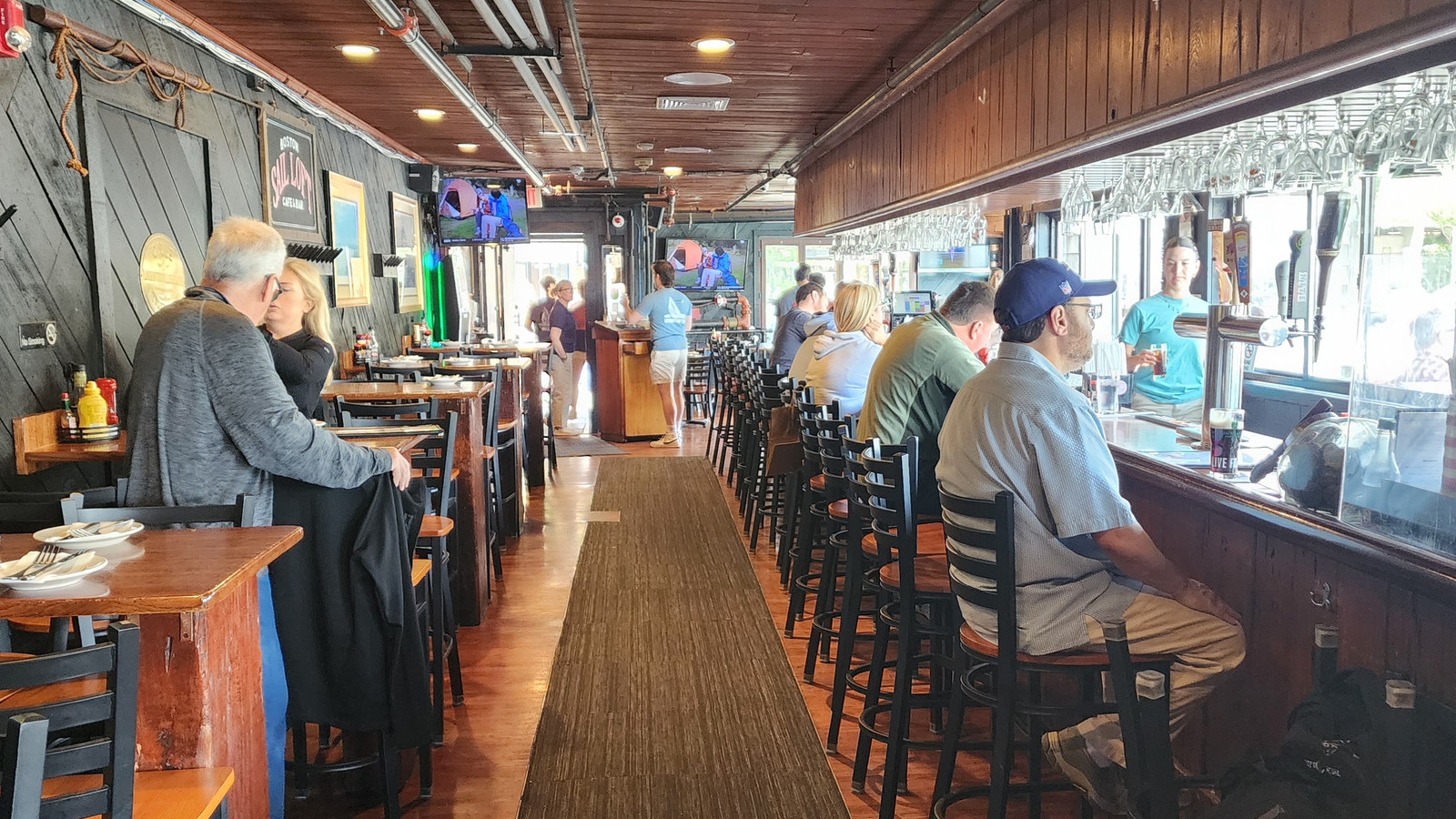long bar and wood ceiling inside Boston Sail Loft with harbor-facing seats