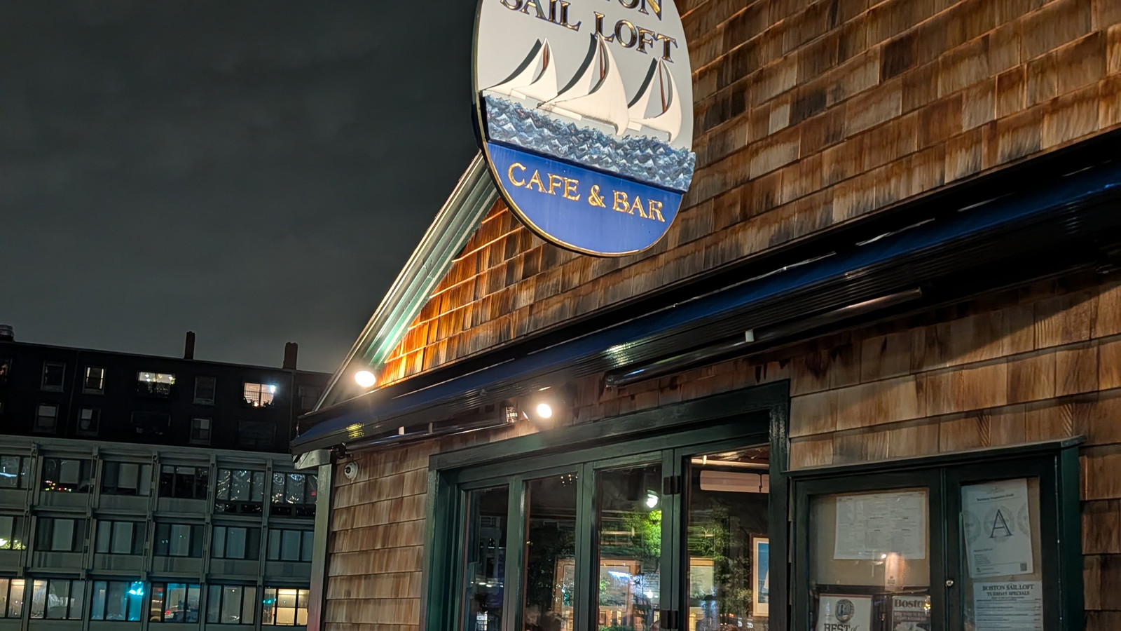 Boston Sail Loft sign shining above the patio after dark