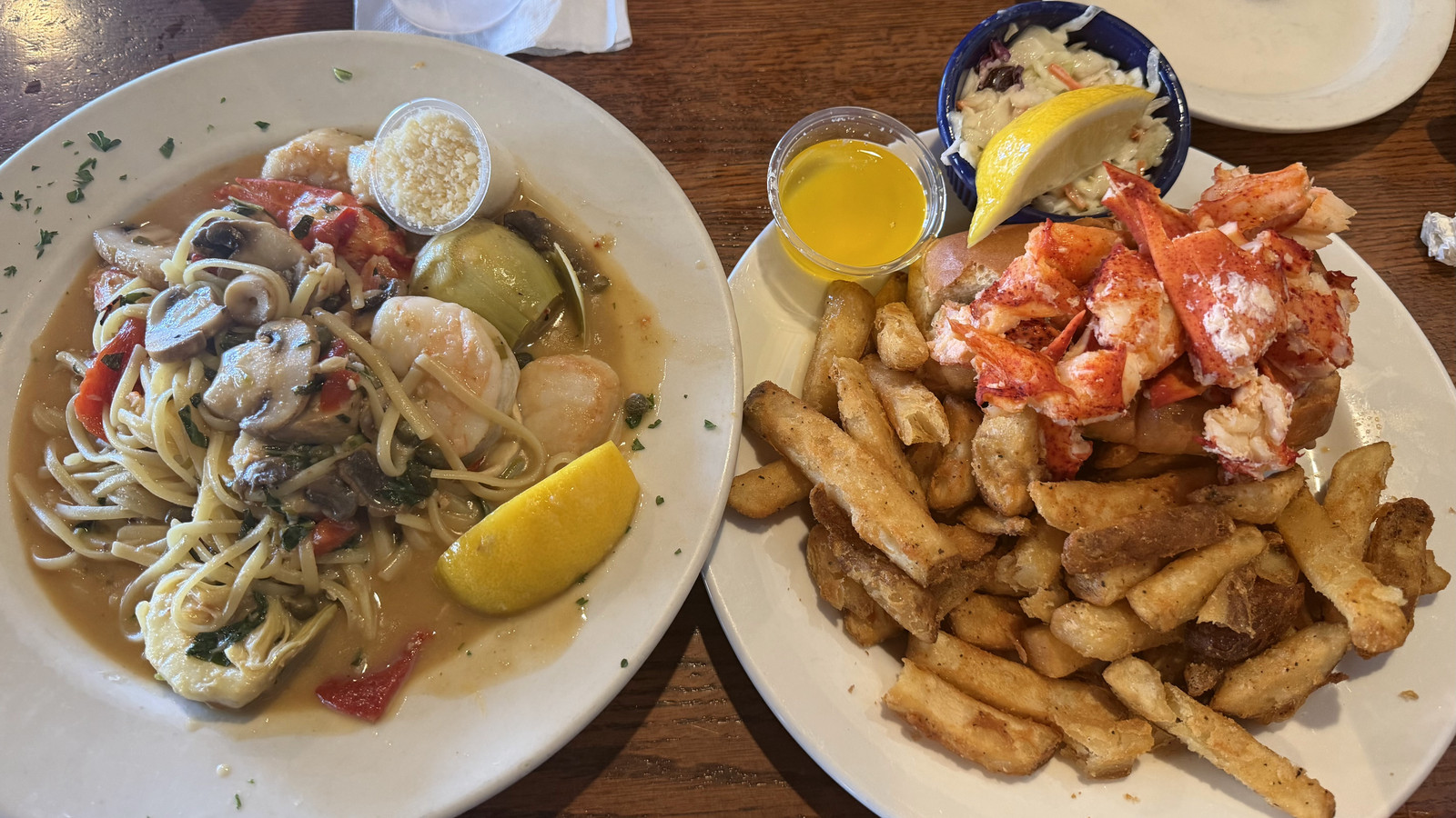 seafood pasta beside a lobster roll and fries at Boston Sail Loft