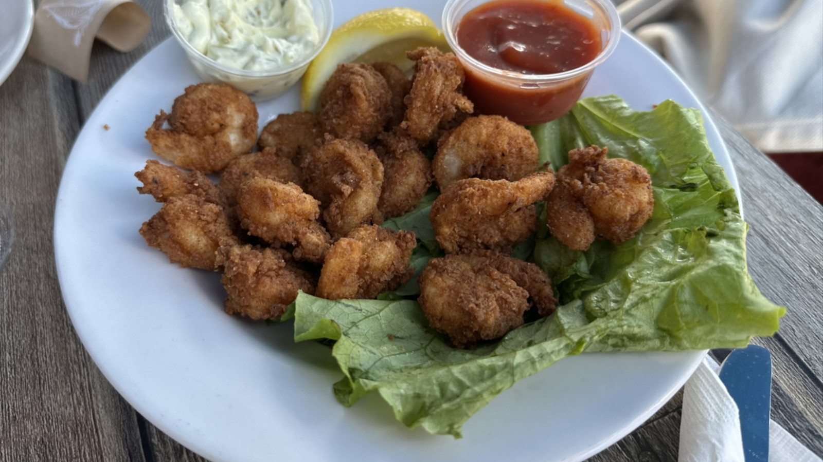 fried seafood bites with dipping sauce on a patio table at Boston Sail Loft