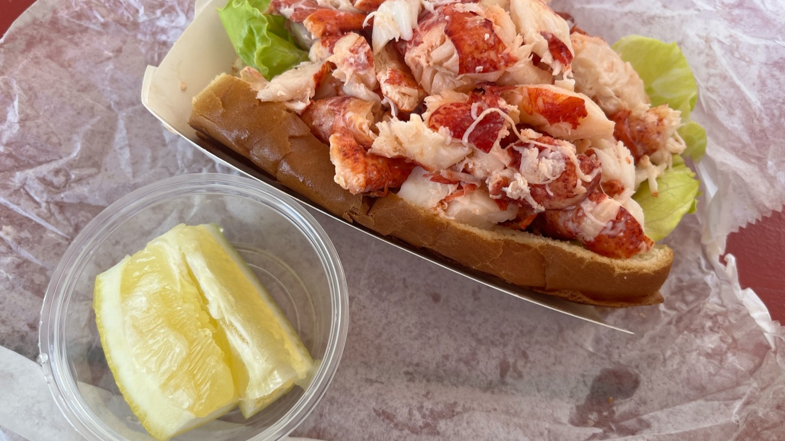 Lobster roll packed with big pieces of meat and served with lemon wedges.