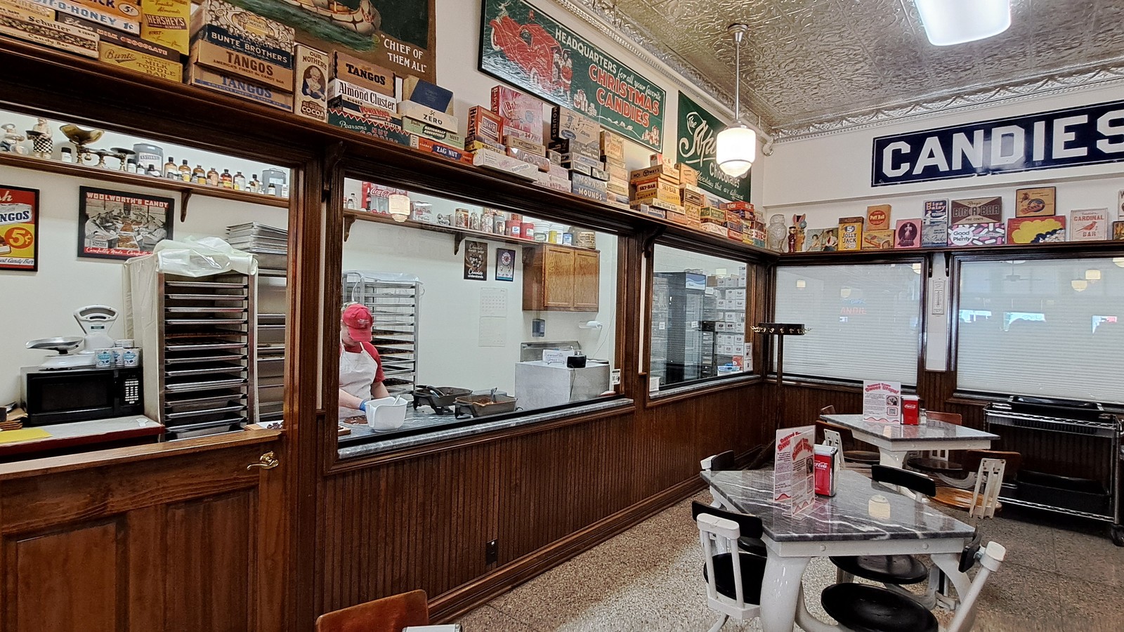 Candy kitchen windows, marble tables, and tin ceiling inside Schimpff's Confectionery