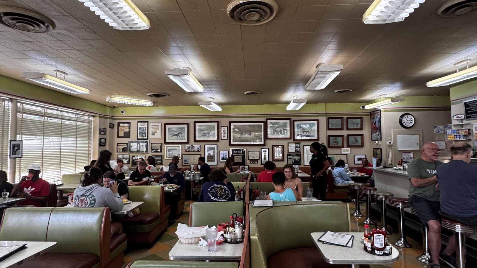 Long dining room with framed walls, green booths, and bright windows inside Silver Skillet
