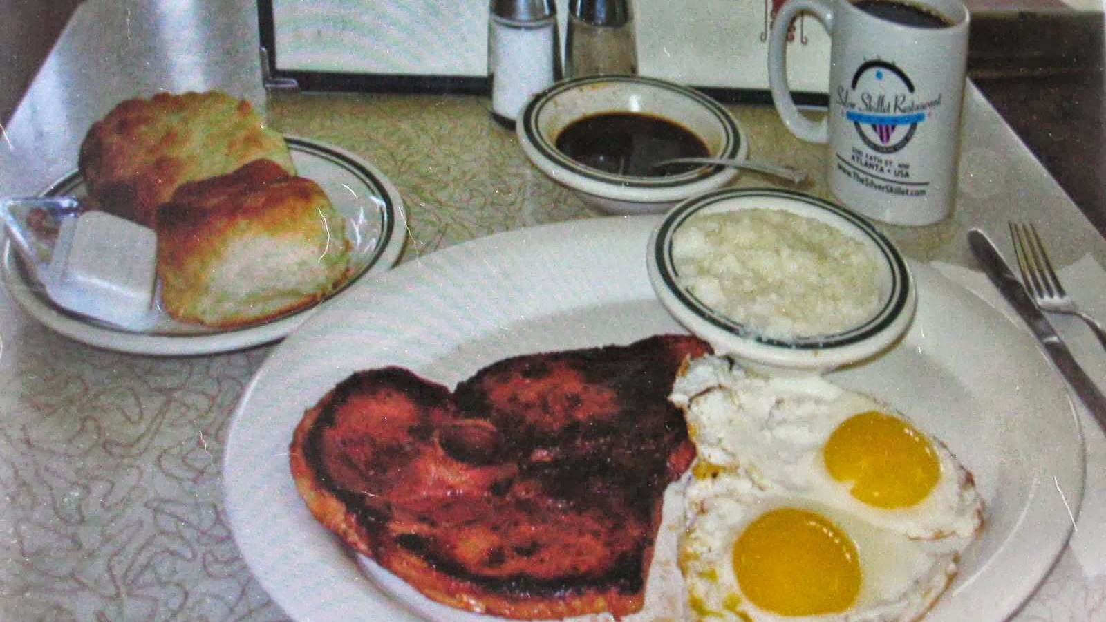 Country ham, sunny-side-up eggs, grits, and a biscuit on a Silver Skillet breakfast plate