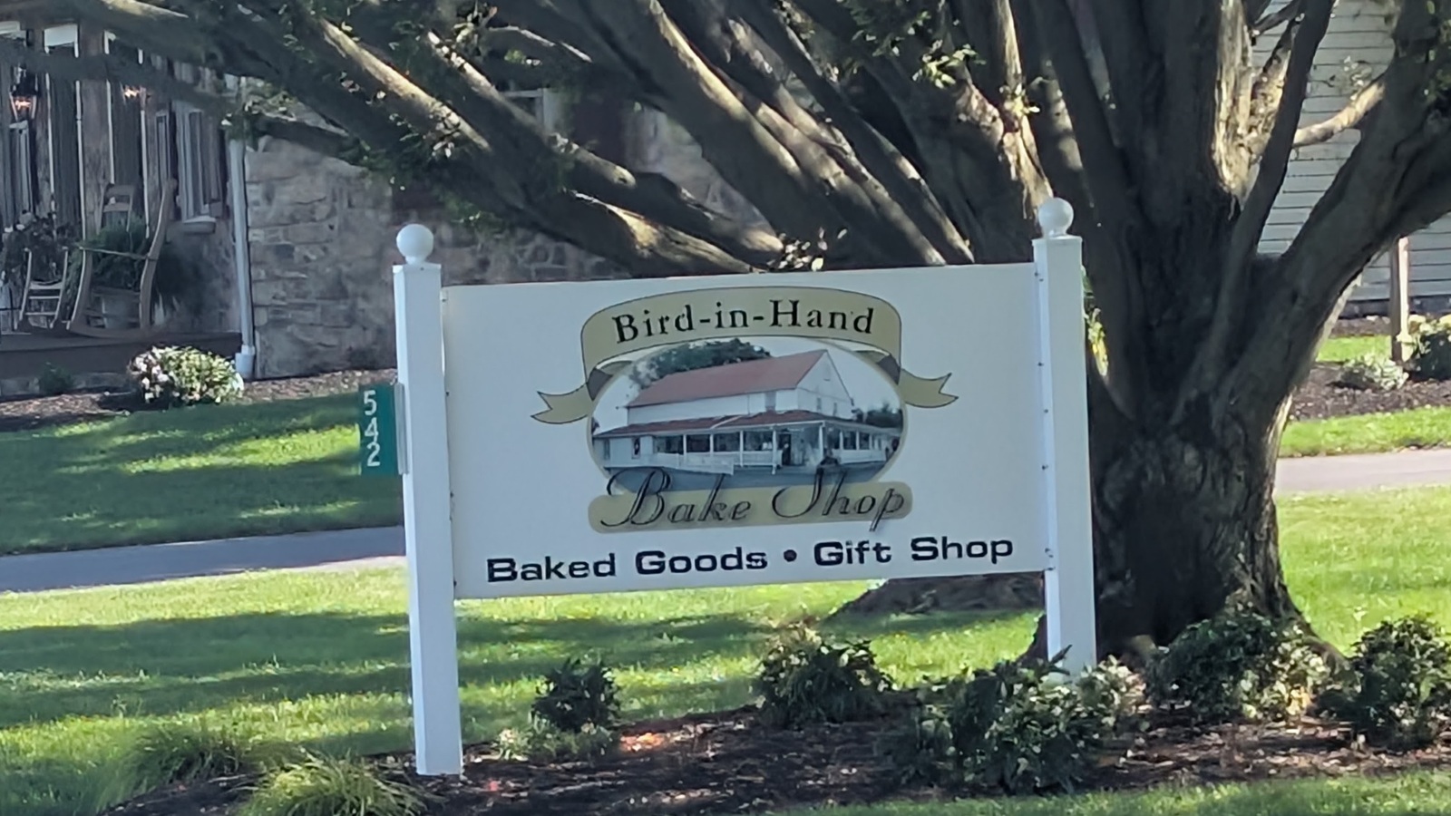 Roadside Bird-in-Hand Bake Shop sign under a broad shade tree