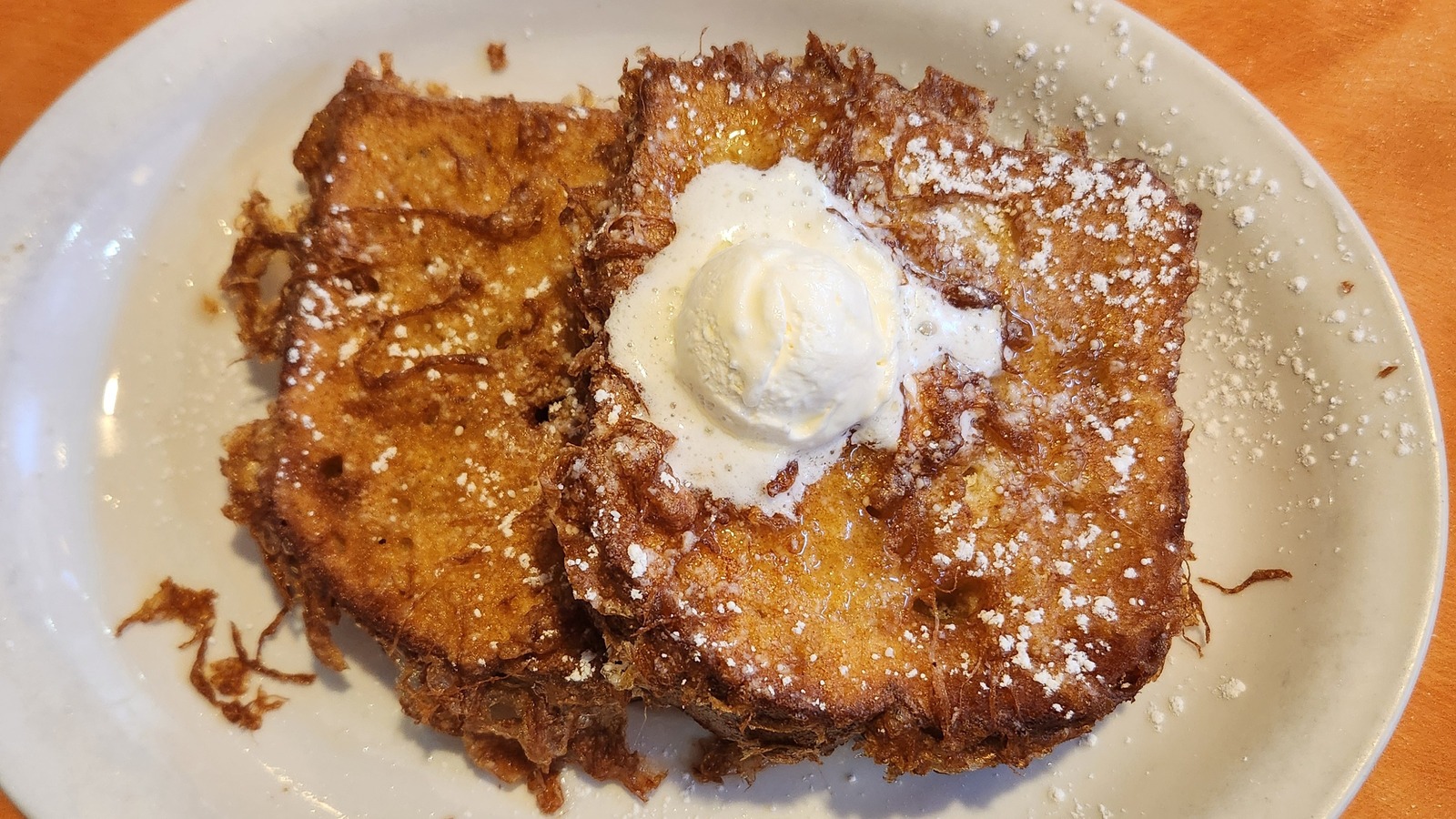 Deep-fried French toast with powdered sugar and a scoop of butter at Original Breakfast House
