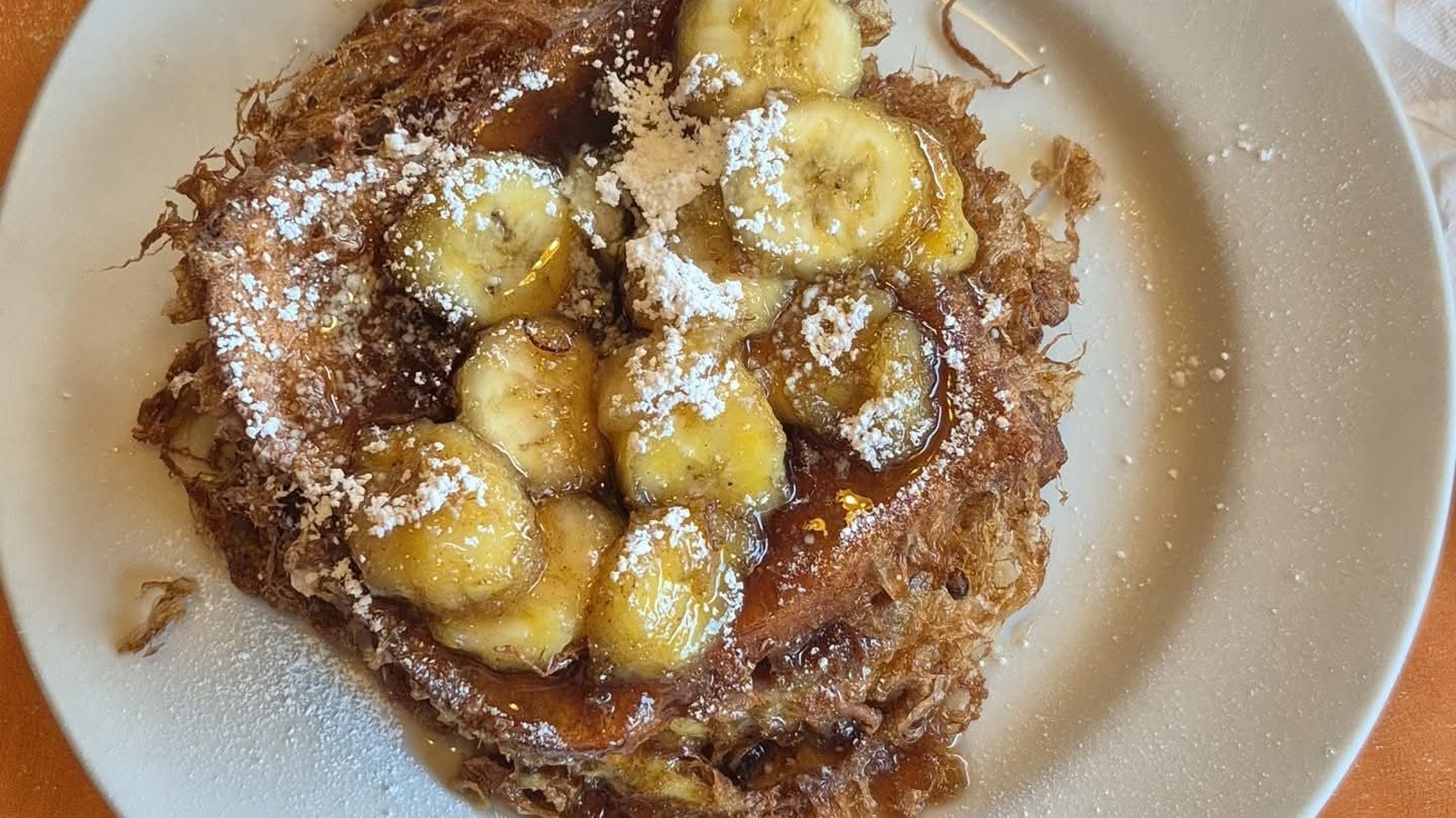 Banana-topped pancakes dusted with powdered sugar at Original Breakfast House