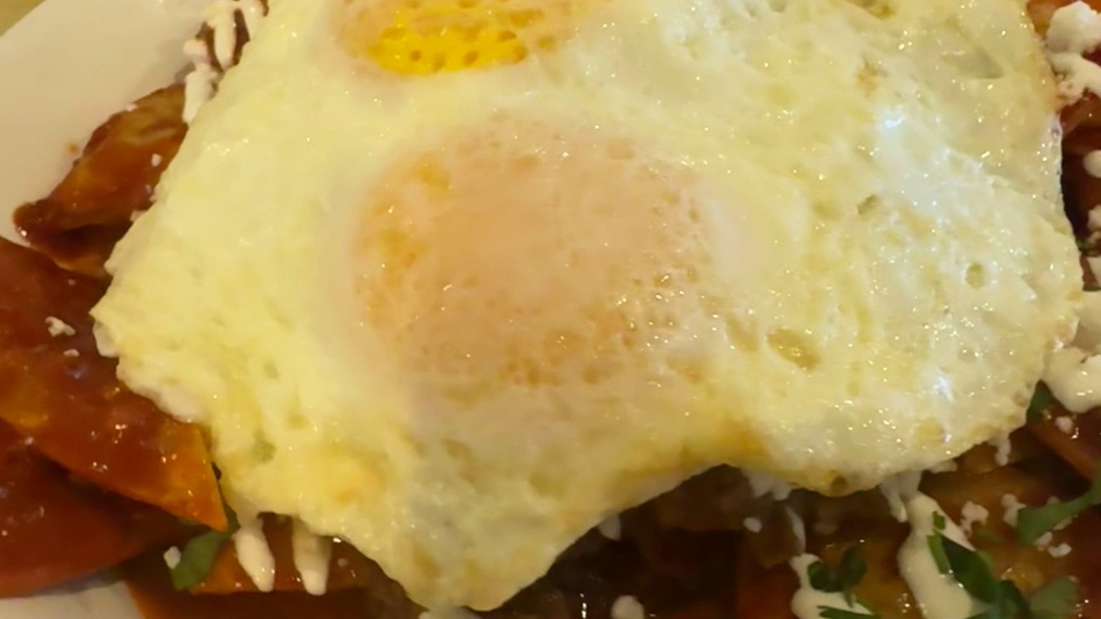 Breakfast plate with sunny-side eggs over a red-sauced al pastor style hash at Original Breakfast House