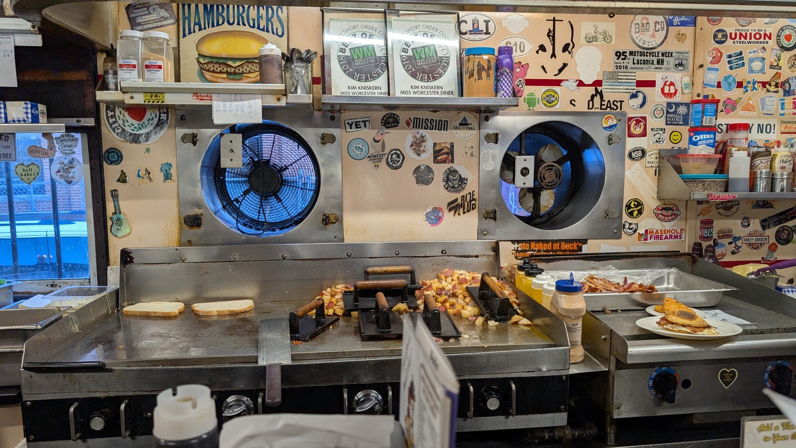Flat-top grill with home fries and breakfast plates inside Miss Worcester Diner