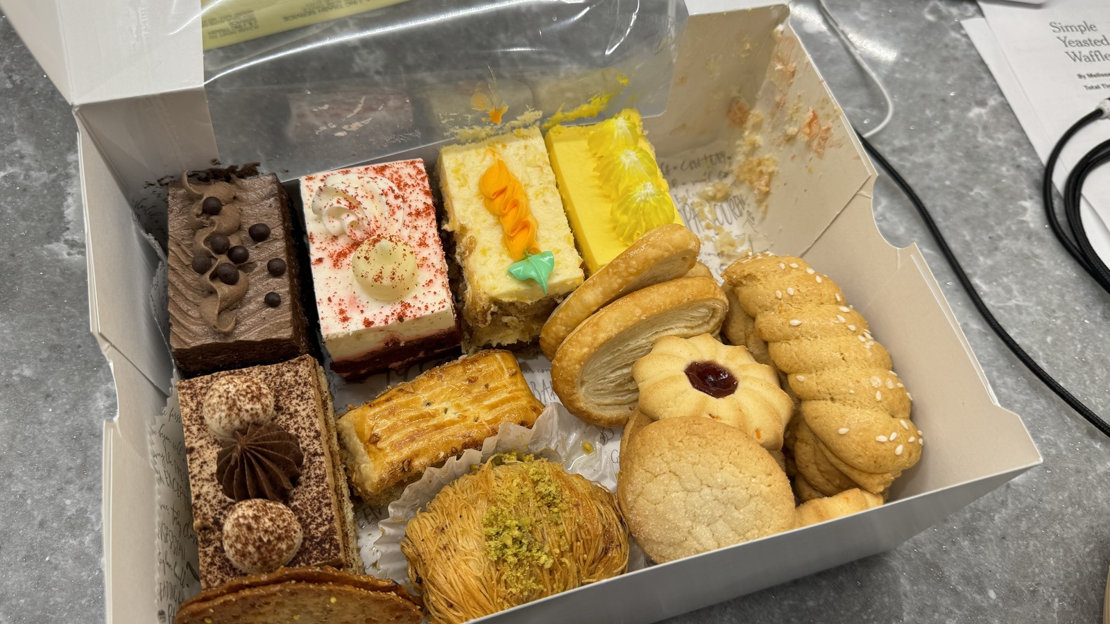 A pastry box packed with cake slices, cookies, and filled pastries from Classic Bakery