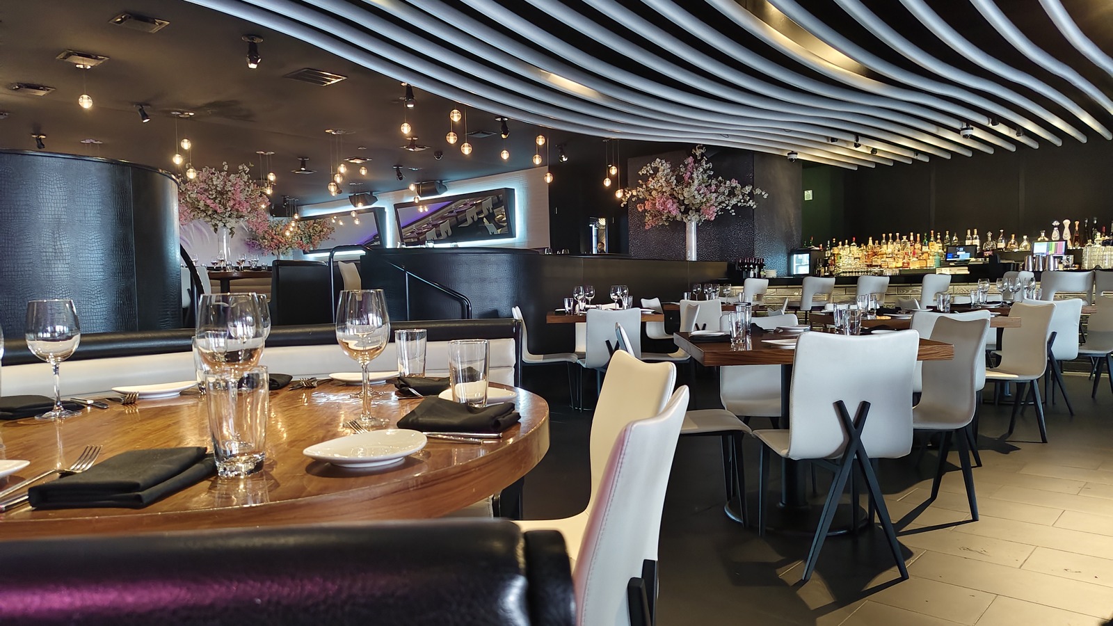 The main dining room and bar at STK Orlando with sculpted ceiling lines and floral arrangements