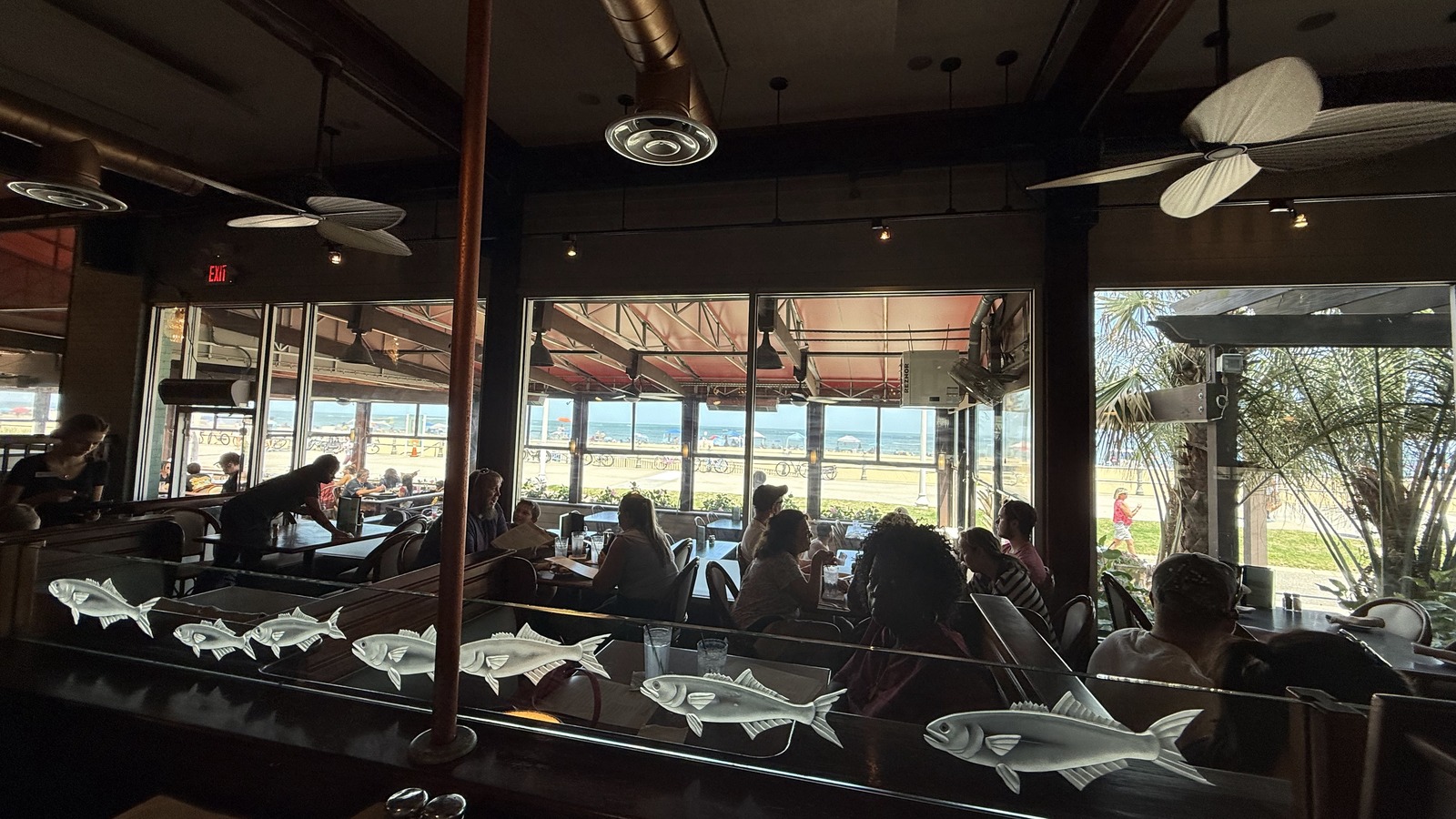 Dining room tables and broad ocean-facing windows inside Waterman's Surfside Grille