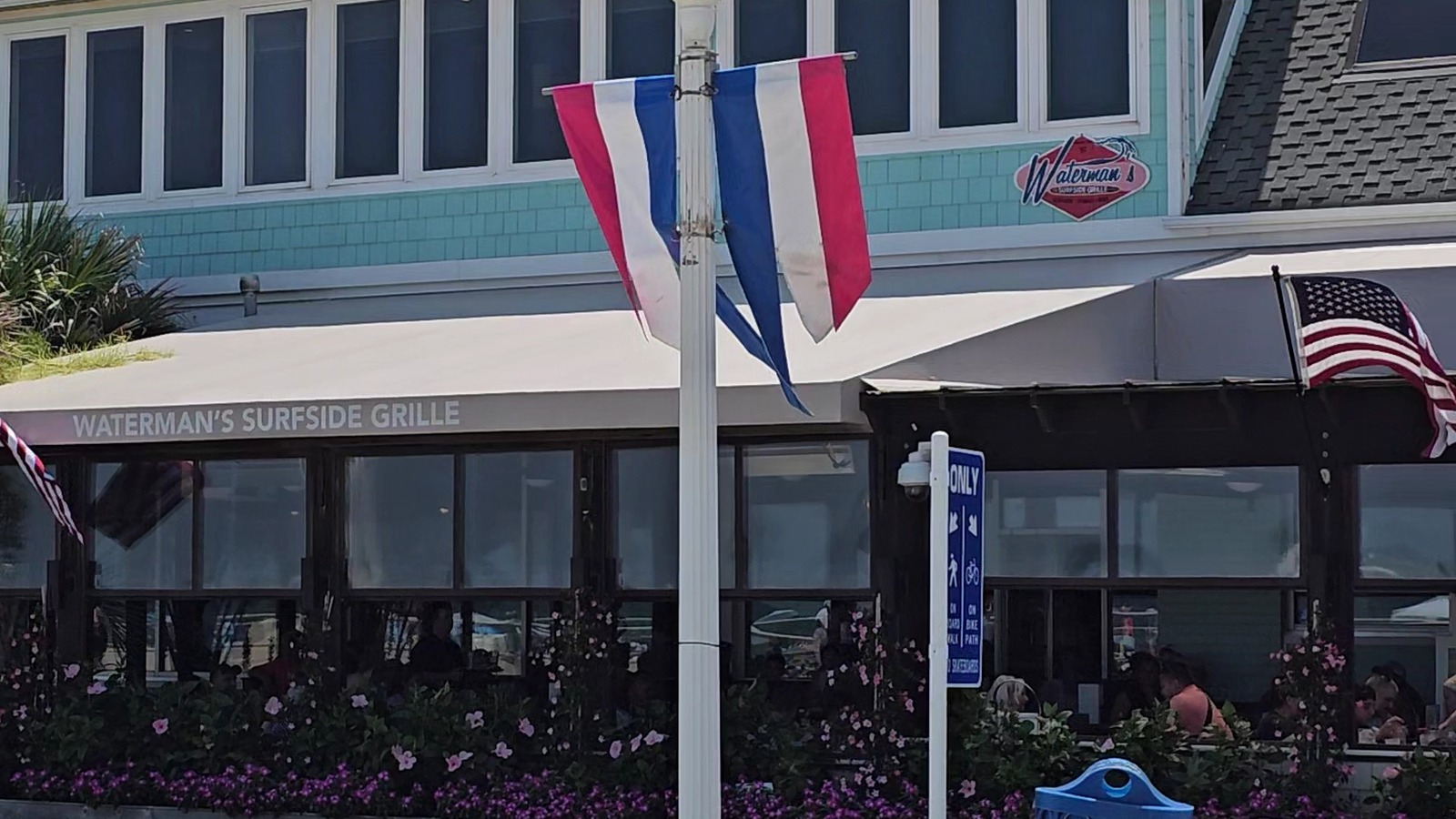 Front patio, flags, and Waterman's Surfside Grille sign along Atlantic Avenue