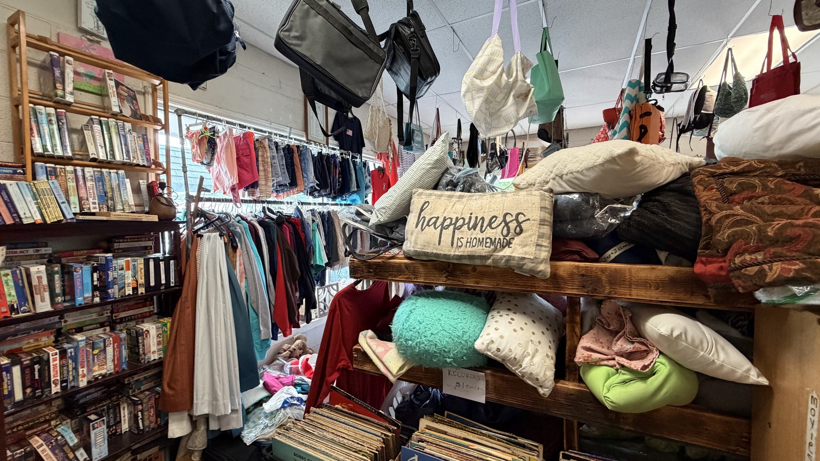Packed shelves, books, and clothing aisles inside She's Thrifty Shop in Johnson City