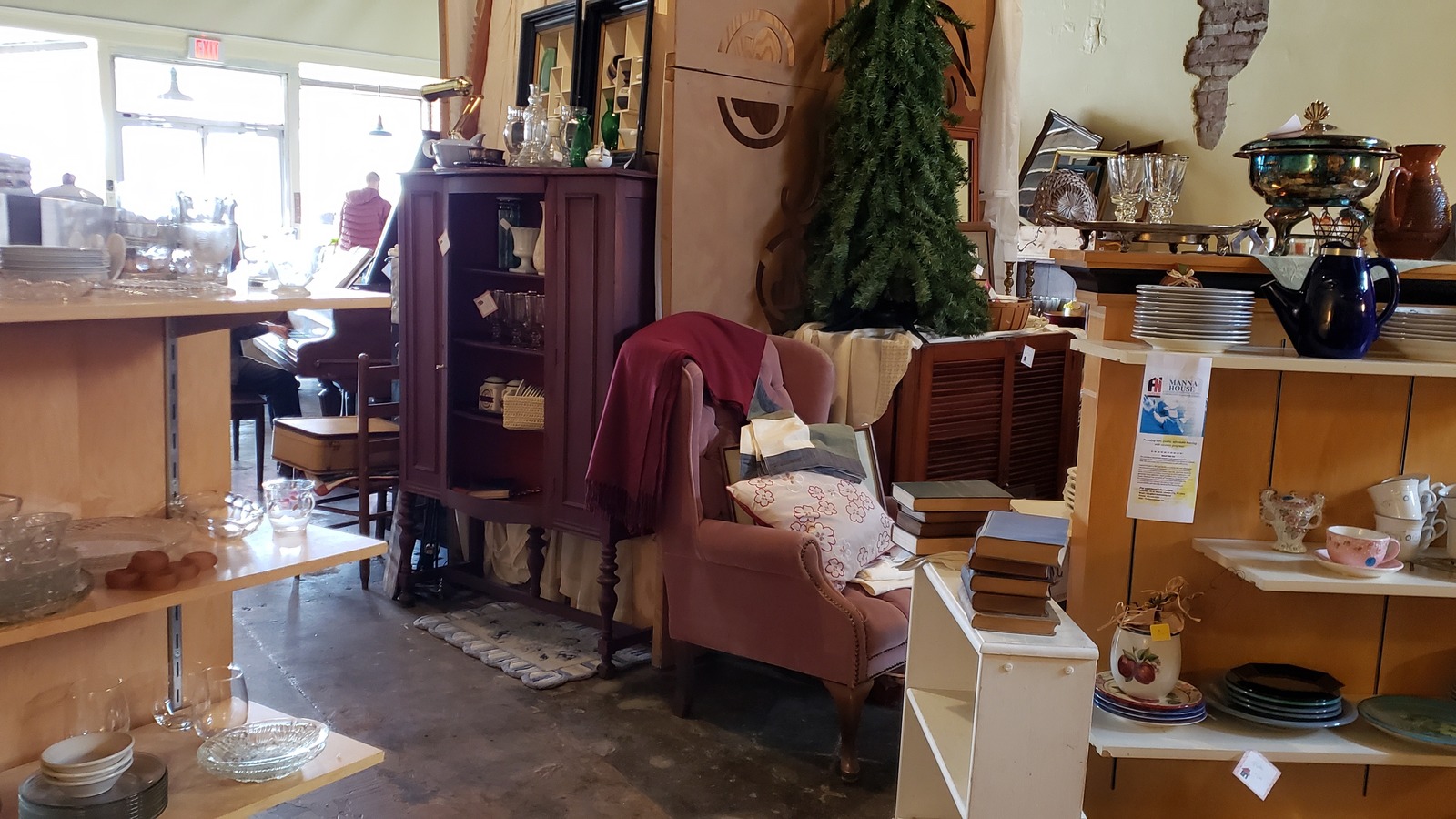 Furniture and decor arranged along a bright aisle inside Manna House Thrift Store in Johnson City