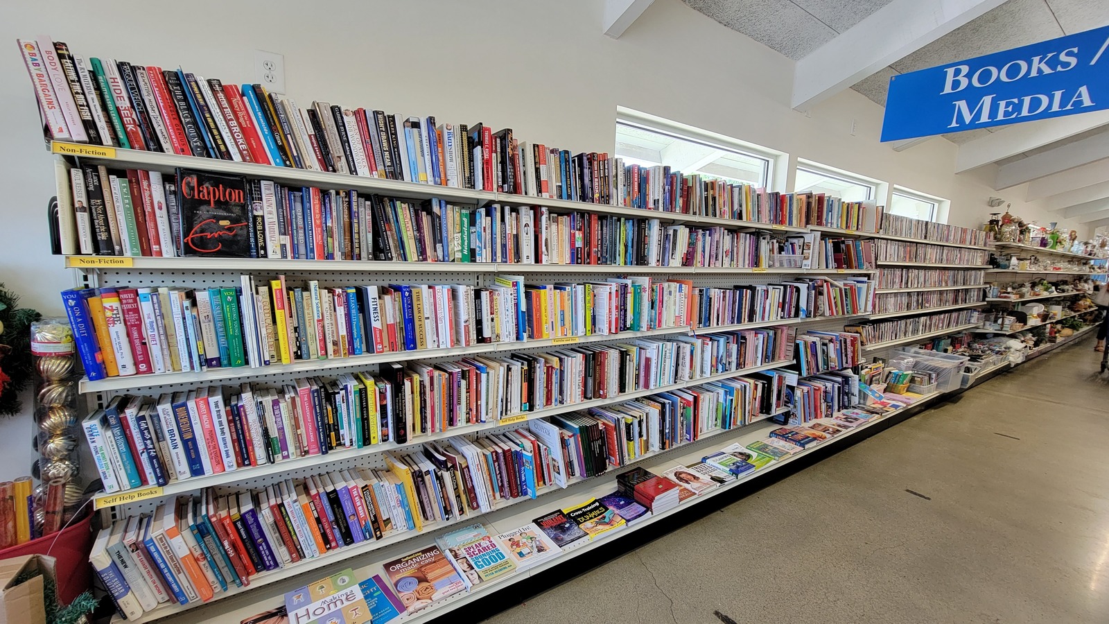 Long wall of books and media shelves inside DAV Thrift Store on General Booth Boulevard