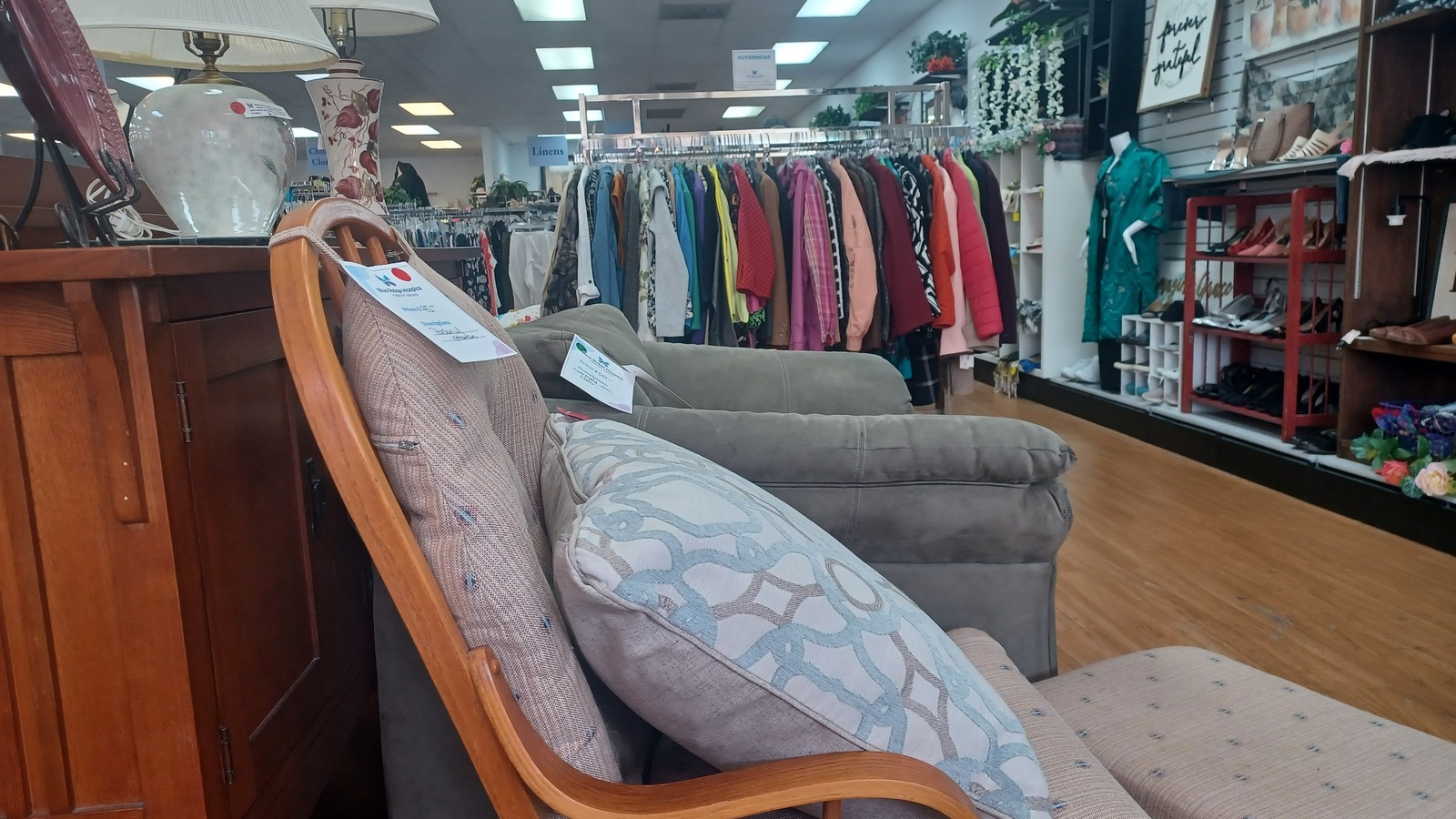 Furniture vignette and clothing racks inside Blue Ridge Care Winchester East Thrift Shop