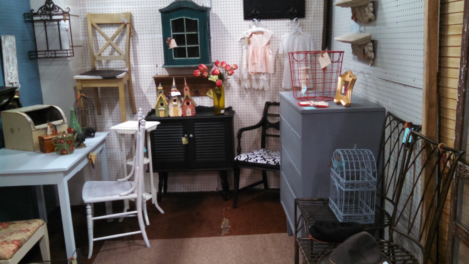 A painted cabinet, antique chairs, and small decor displays inside Foothills Flea Market & Antiques in Fort Collins