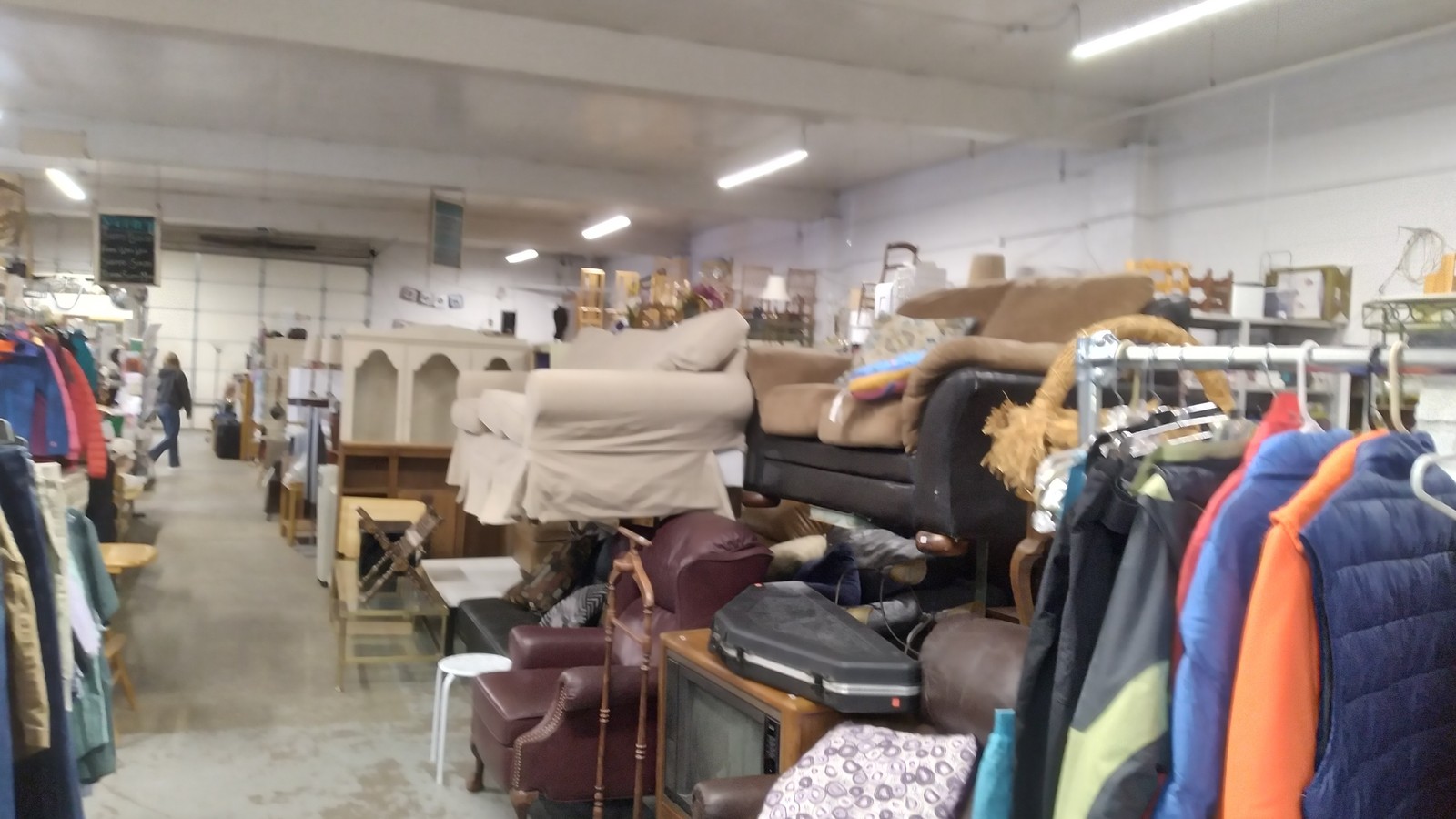Clothing racks, furniture, and household items spread across the sales floor at Eco-Thrift in Fort Collins