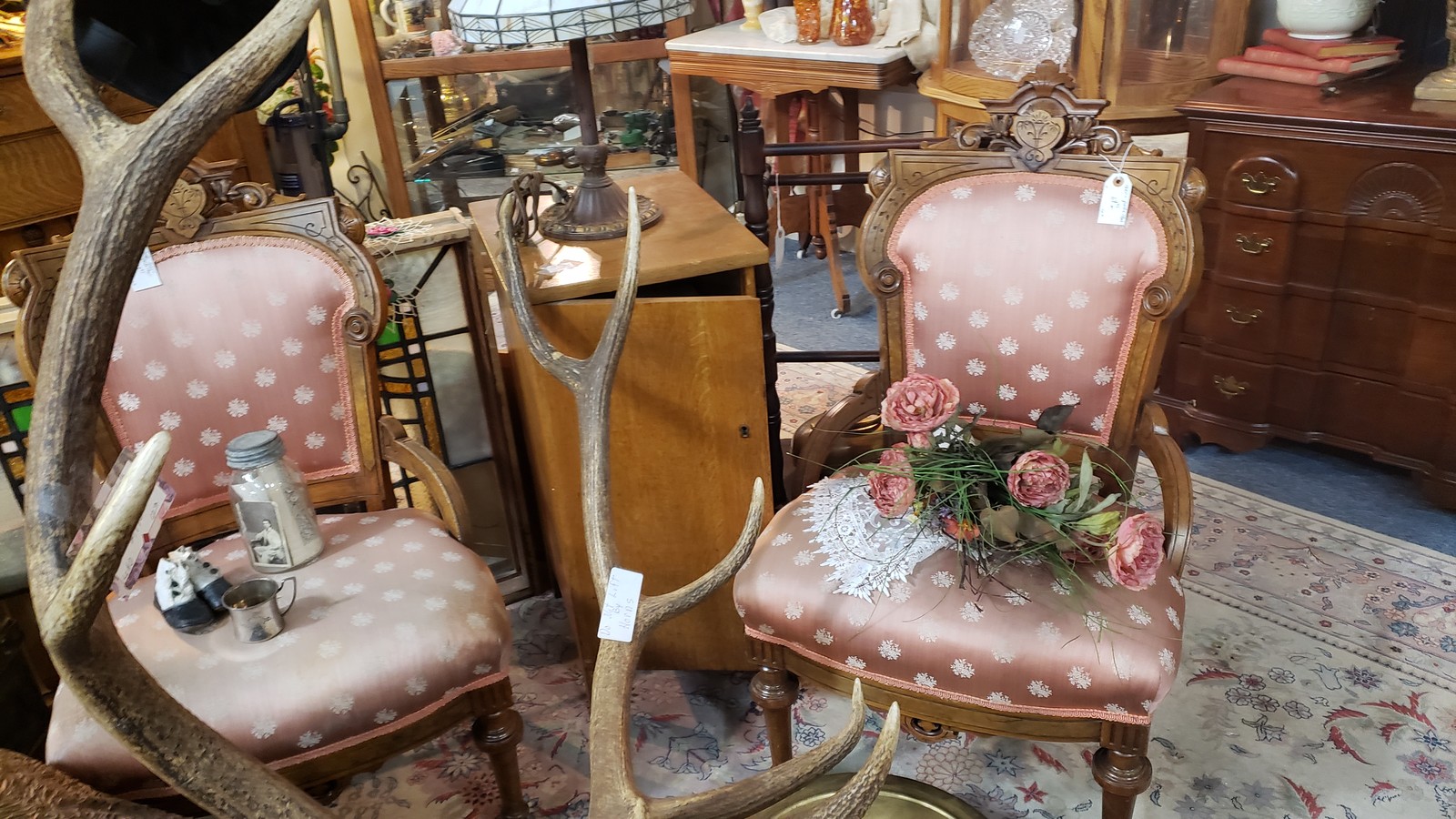 Upholstered antique chairs surrounded by lamps, furniture, and collectibles inside Jarvey Treasures in Fort Collins