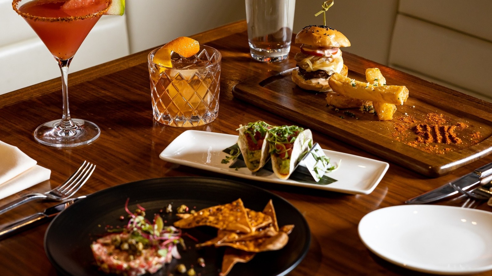 STK table in Orlando with cocktails, sliders, tacos, and small plates arranged on polished wood