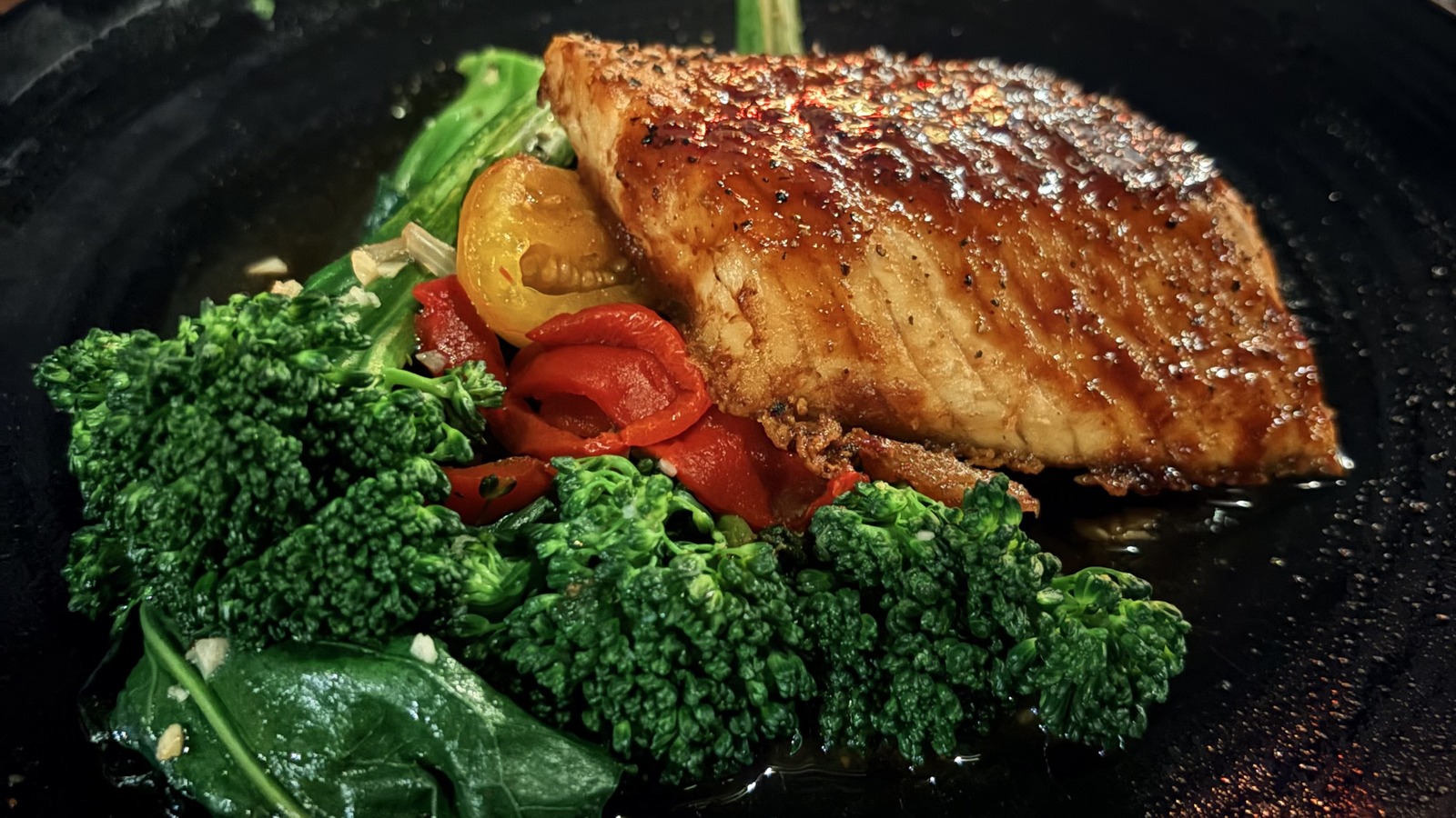 Seared fish entrée at STK Orlando served with bright green broccolini and roasted peppers