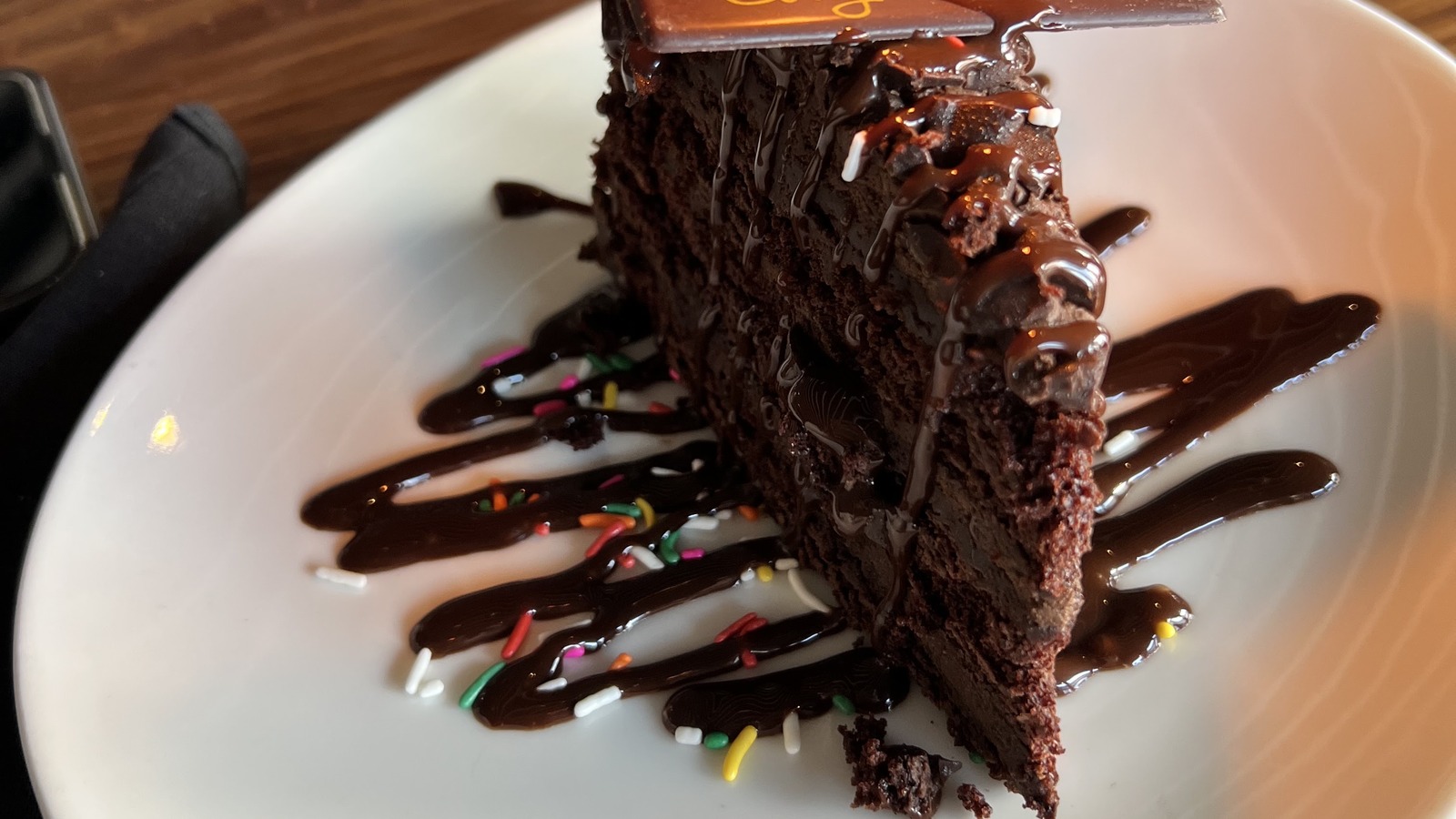 Slice of rich chocolate cake with candle on a white plate at STK Orlando