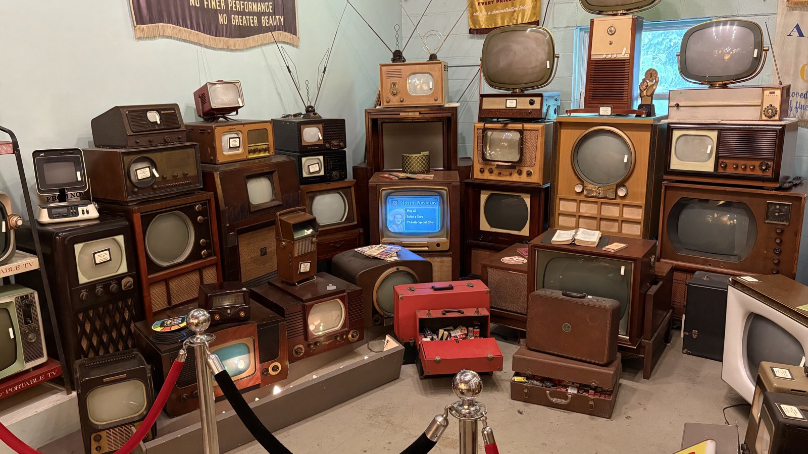 Collection of vintage televisions and media displays arranged floor to ceiling at The Bomb Shelter