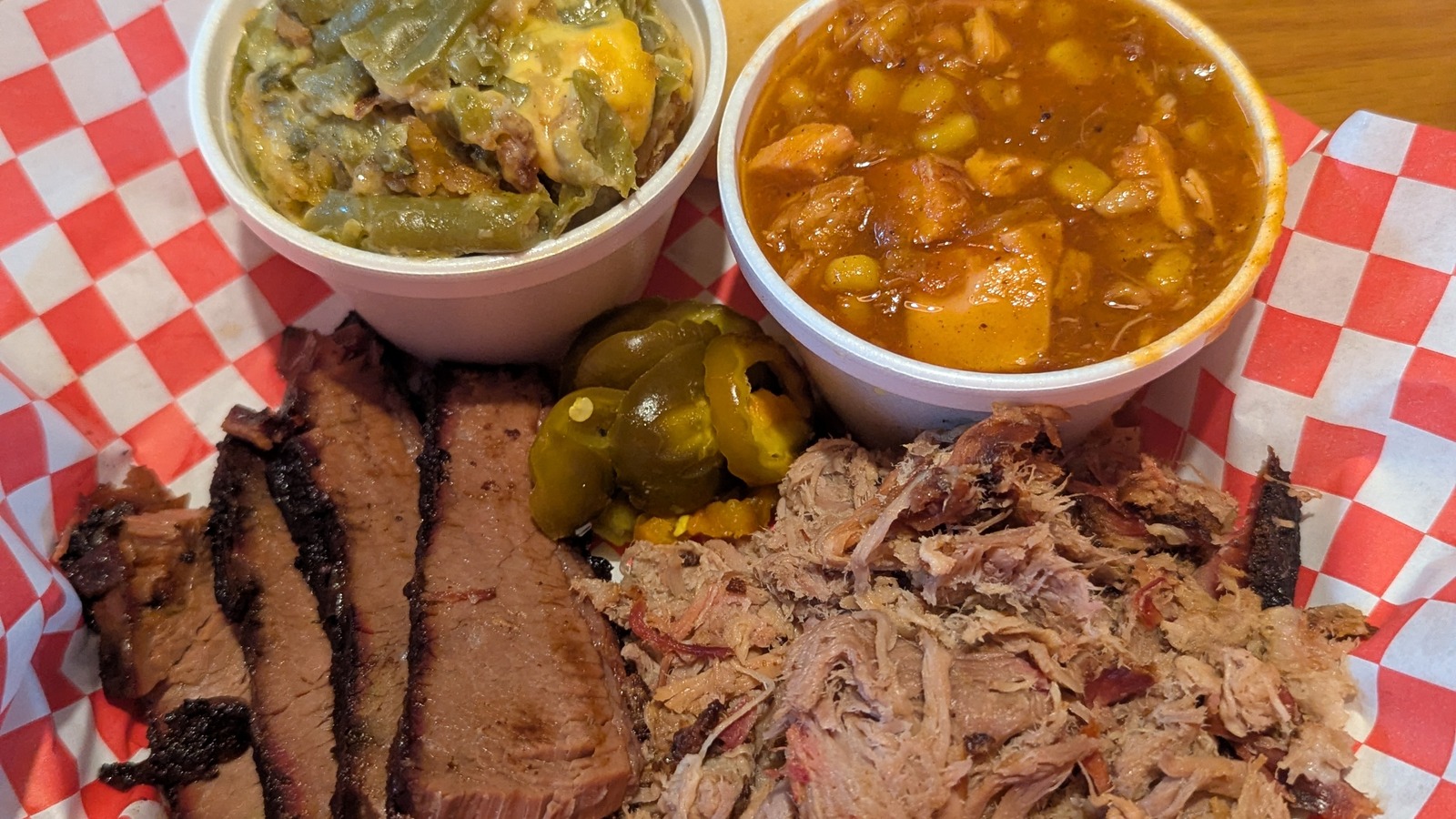 Brisket, pulled pork, sides, and pickles on a red-check tray at JD's Smokehouse