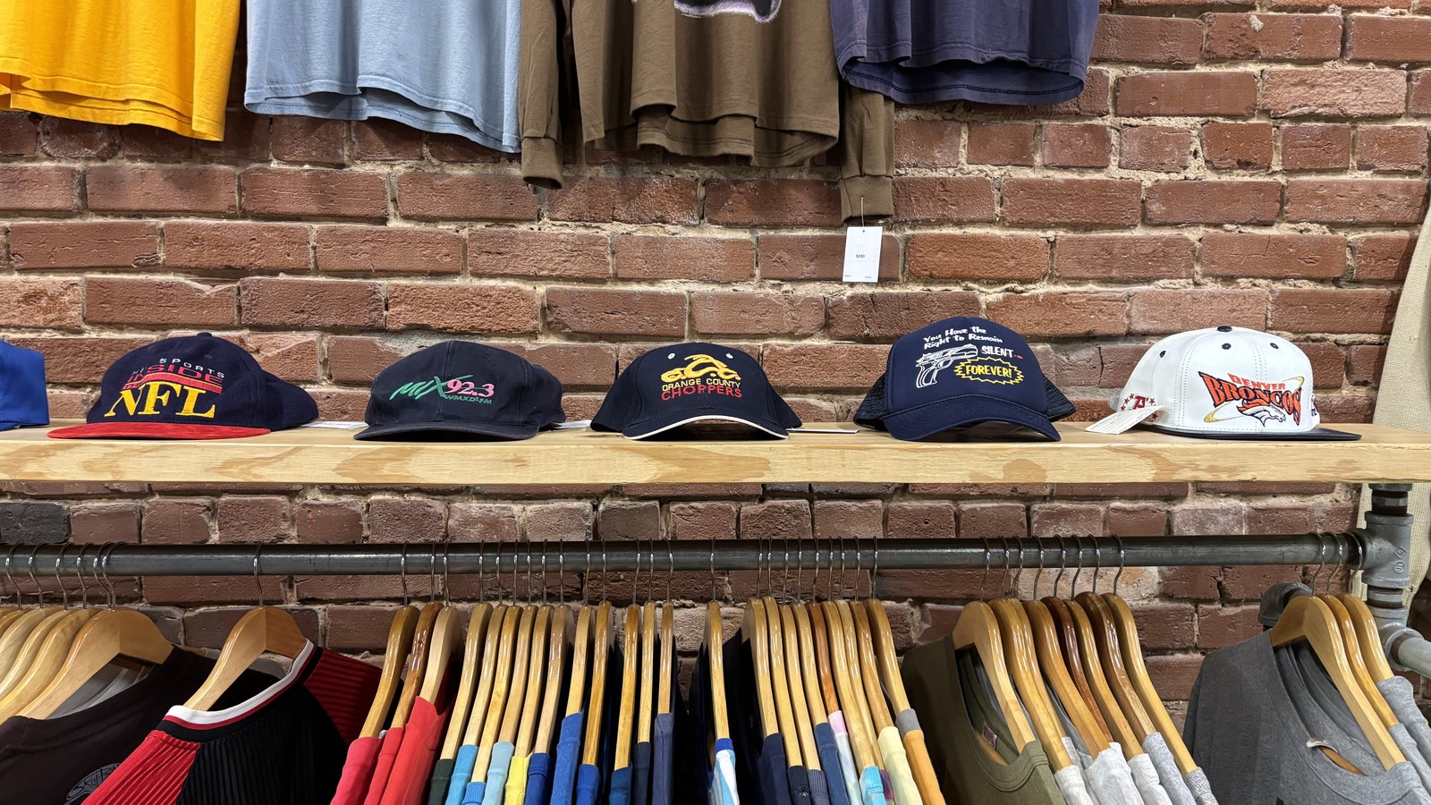 Vintage shirts and hats arranged against a brick wall at Poor Taste in Chattanooga