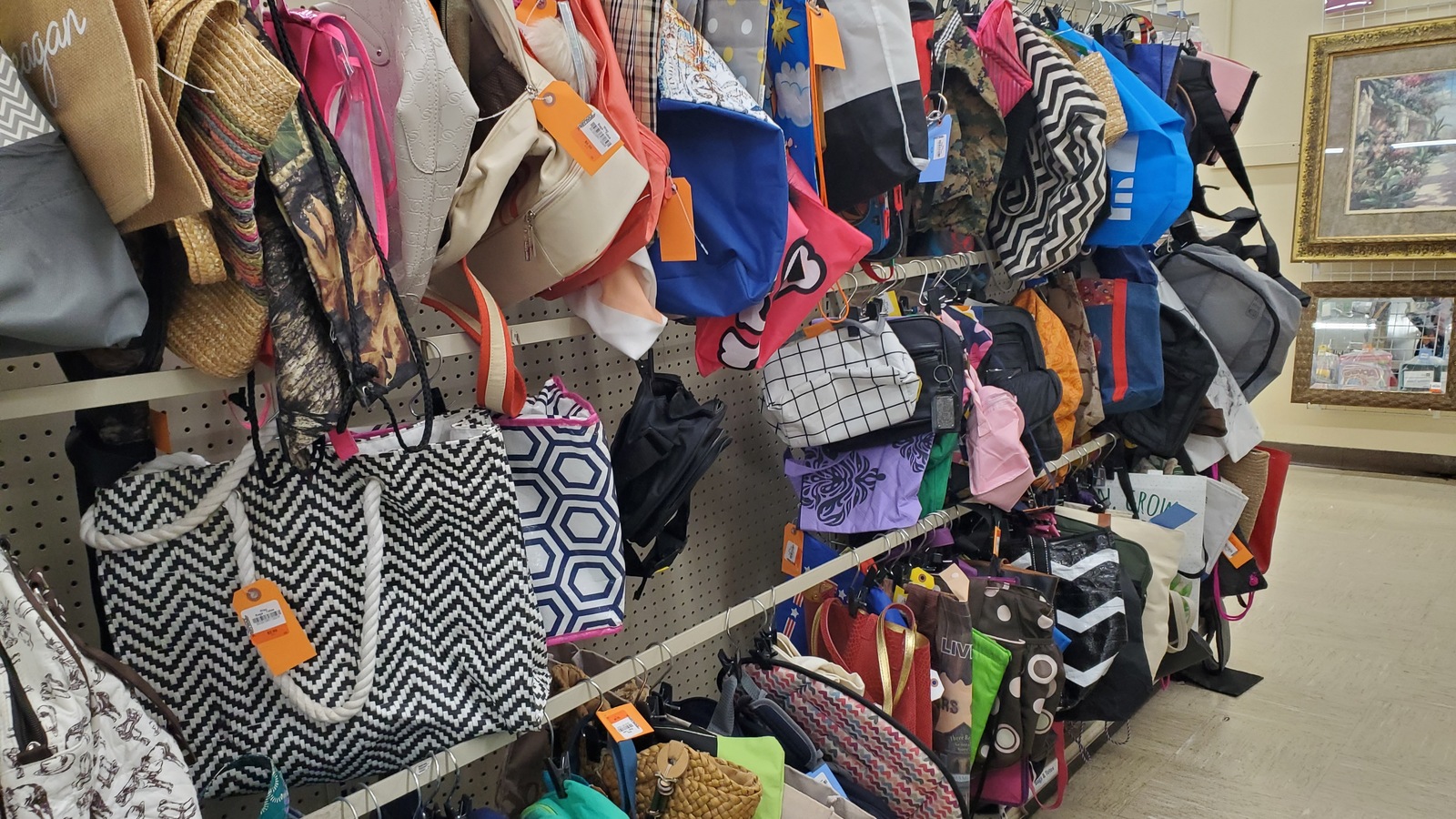 Handbags hanging beside framed art at America's Thrift Store in Jasper