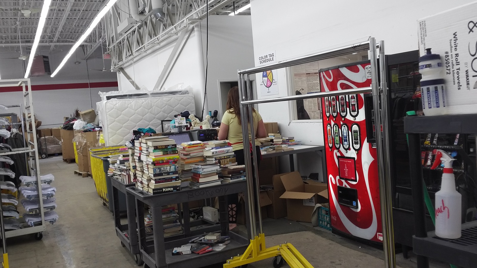 Book tables beside a red arcade cabinet and household goods