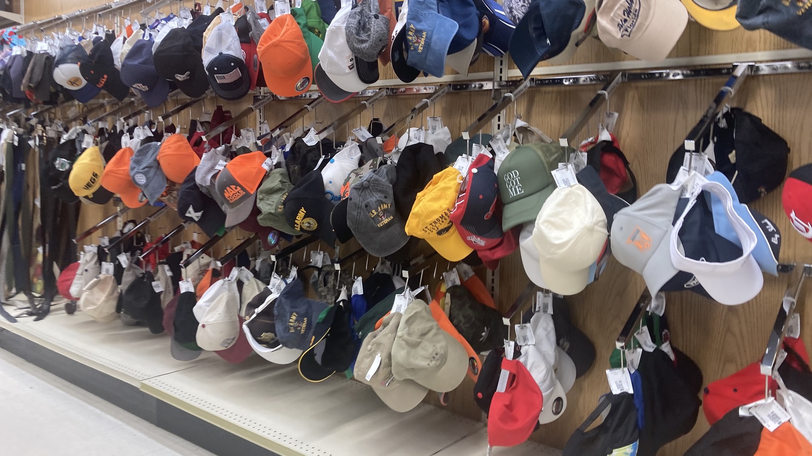 Long wall filled with baseball caps and hats at Valley Thrift Store