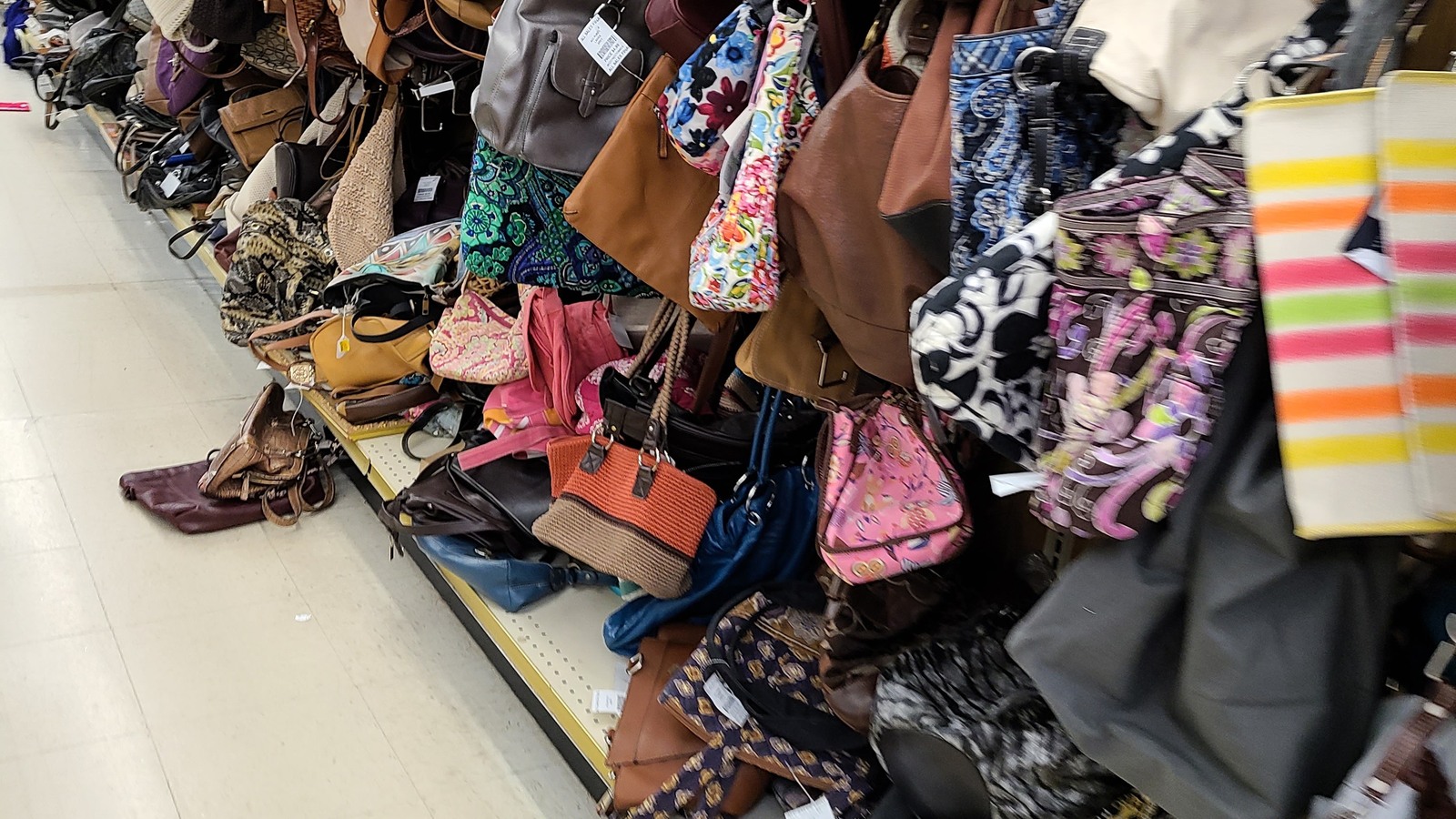 Colorful handbags and purses arranged along an accessories aisle at Valley Thrift Store